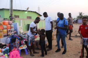 A staff of Enough Grace Foundation dressing a child whiles VMF members looks on